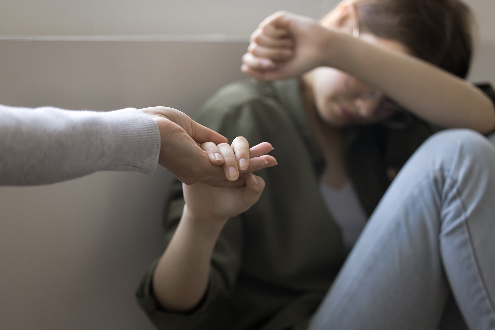 A supportive hand reaching out to a distressed child sitting in a corner. Signs of Child Abuse