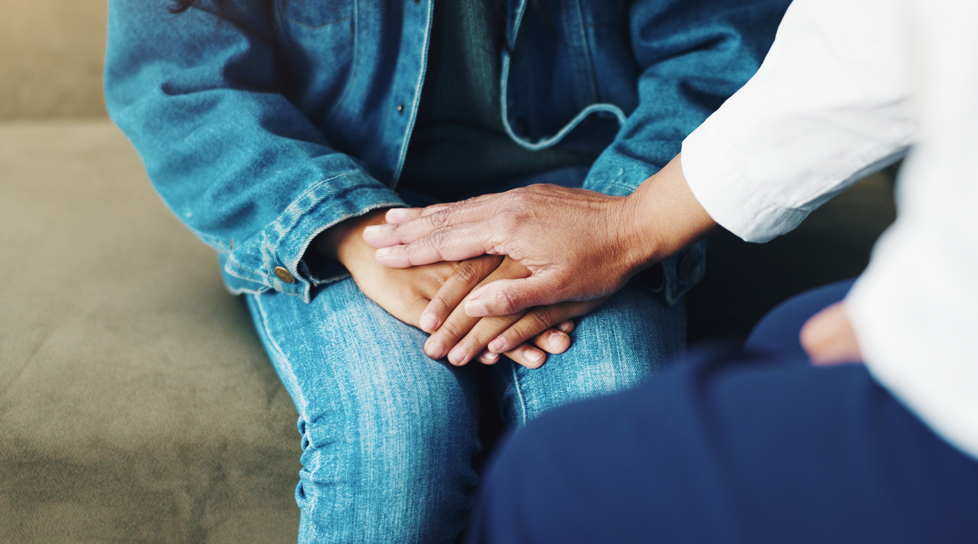 Close-up of a supportive hand placed over a child’s hands, symbolizing care and protection for victims of sexual abuse.