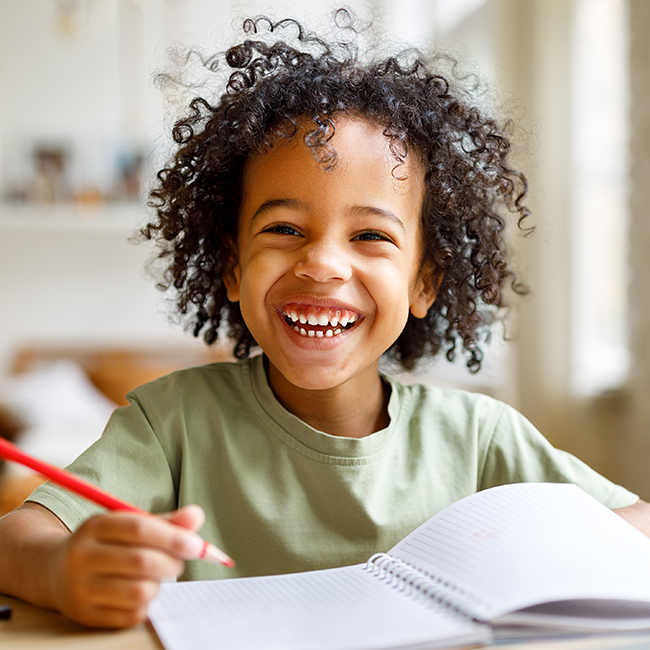 Happy child writing in a notebook, representing the positive impact of a child advocacy and adoption lawyer in protecting children's rights.